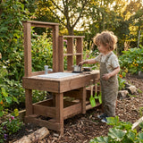 Child playing with a wooden outdoor play kitchen in a garden.