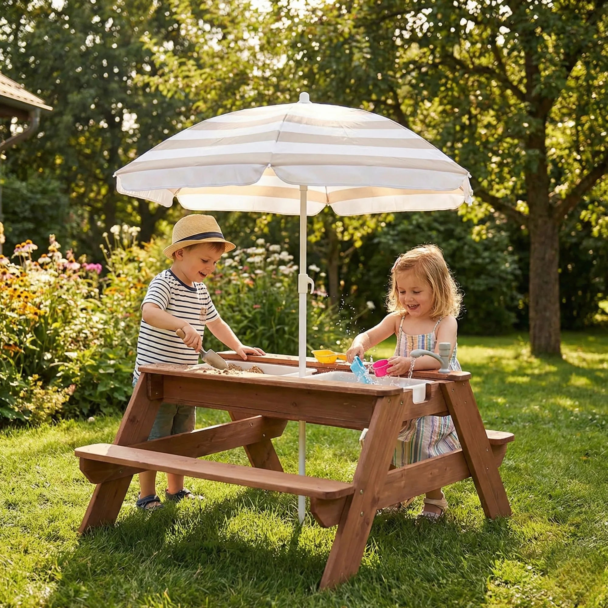 Two children playing at a wooden picnic table with a striped umbrella in a garden.