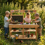 Children playing with a wooden play kitchen set outdoors.